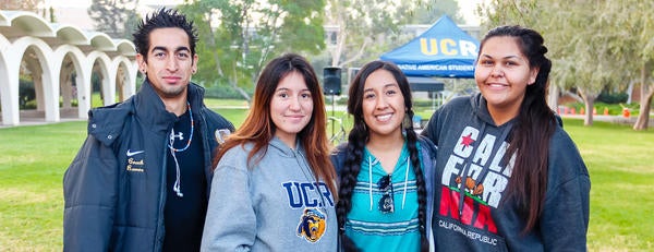 Four NASP students stand arm in arm in front of the iconic arches of UCR's Tomás Rivera Library