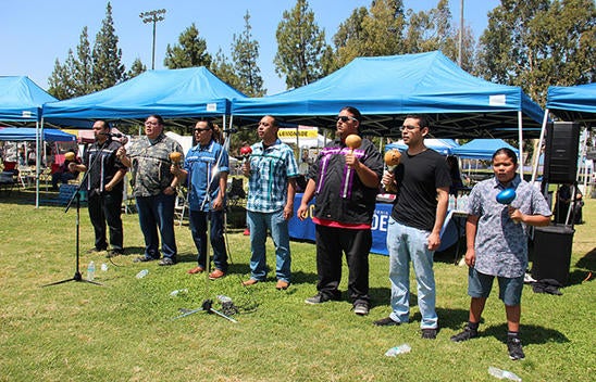 Seven Native performers sing and play instruments at the NASP Pow Wow