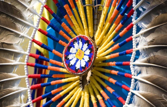 Feathers, threading, and floral beading combine to create a ceremonial artwork